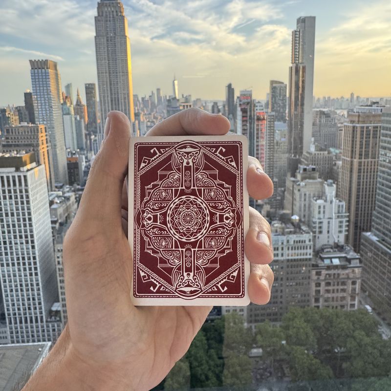 A Fragments card held up against the Manhattan skyline at sunset, the full back design visible