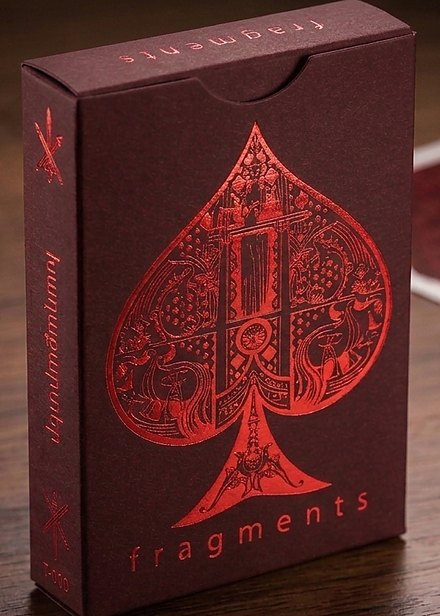 The Fragments tuck box, deep red with an ornamental ace of spades and the word fragments